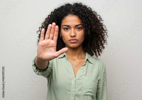 Woman with curly hair holding hand up in a stop gesture pose look isolated on white background