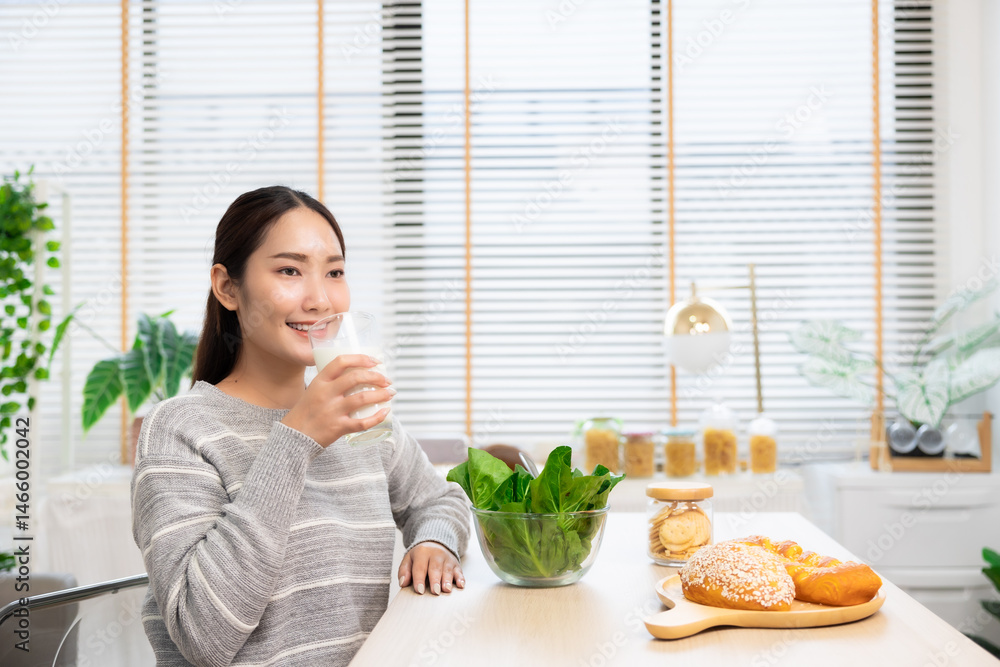 Asian woman drinking milk and eating vegetable breakfast in kitchen at home . Asian woman drinking milk and eating vegetable breakfast in kitchen at home .