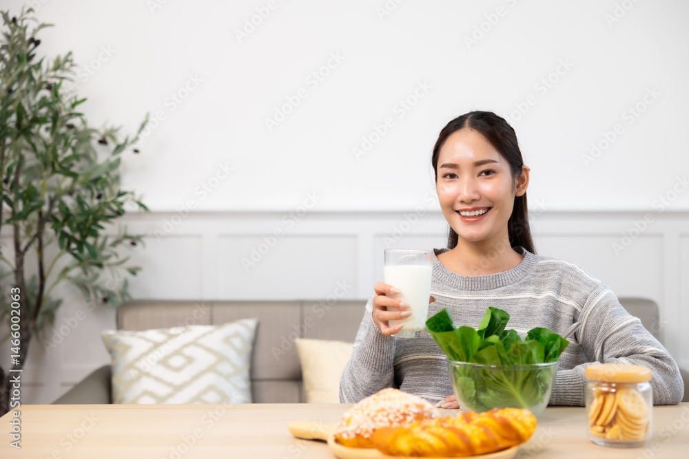 Asian woman drinking milk and eating vegetable breakfast in kitchen at home . Asian woman drinking milk and eating vegetable breakfast in kitchen at home .
