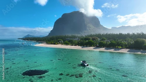 Aerial footage of a boat navigating crystal-clear waters off Le Morne beach, Mauritius, with the iconic Le Morne Brabant mountain rising in the background