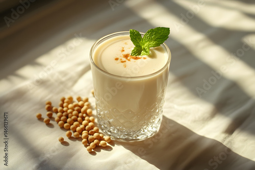 Obraz na płótnie Soy milk in transparent glass with fresh mint on top and soybeans gently arranged on wooden surface, captured natural morning light to highlight plant-based nutrition and elegance w salonie