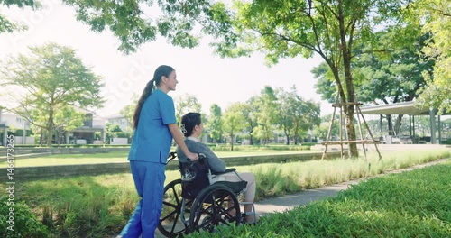 Portrait young Asian nurse showing compassion and support to elderly woman in wheelchair at outdoor garden, caregiving with trust and kindness
