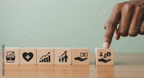 Hand Reaching Wooden Block with Downward Arrow Icon Among Healthcare Symbols on Tabletop in Muted Green Background