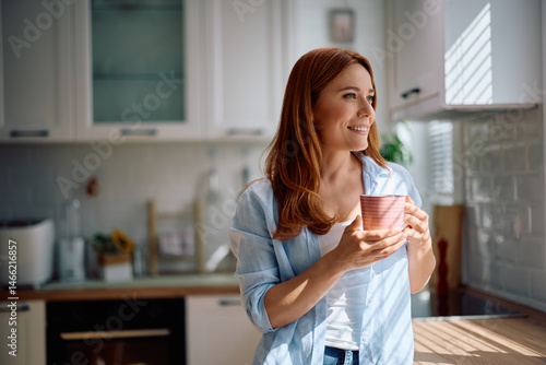 Foto Happy woman day dreaming while having cup of tea at home.