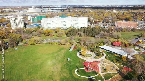 City park with a large building in the background. The park is full of trees and grass