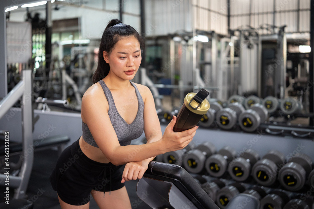 Fototapeta premium A woman in workout clothes drinking a health drink