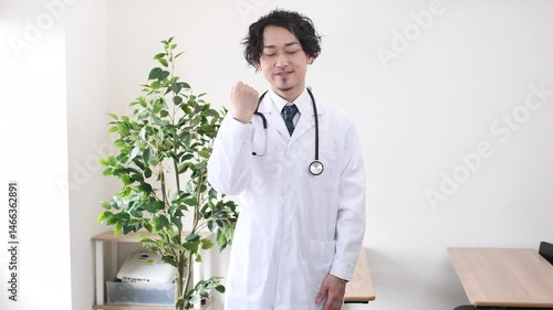 ガッツポーズをするアジア人の男性医師