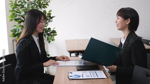 打ち合わせをするスーツ姿のアジア人女性達