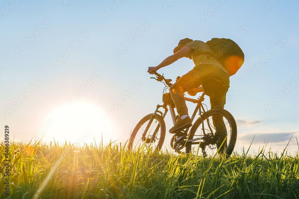 Fototapeta premium Rear view. Cyclist riding a bike in a field.