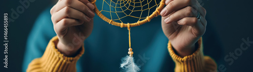 Obraz na płótnie Closeup hands holding handmade dreamcatcher with yellow thread, wooden beads, and white feather, cozy and creative atmosphere w salonie
