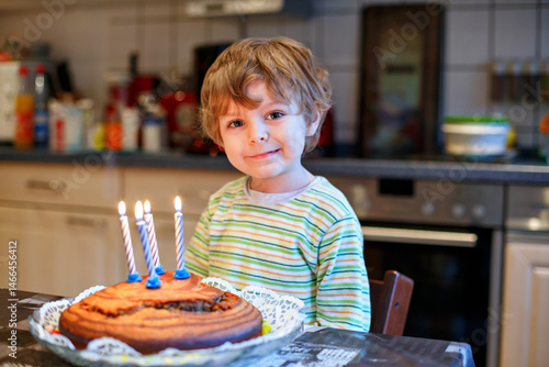 Foto Adorable four year old boy celebrating his birthday and blowing off the candles on the cake, indoor