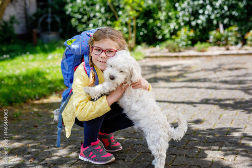Foto Little girl with her school satchel after school and her cute maltese puppy dog