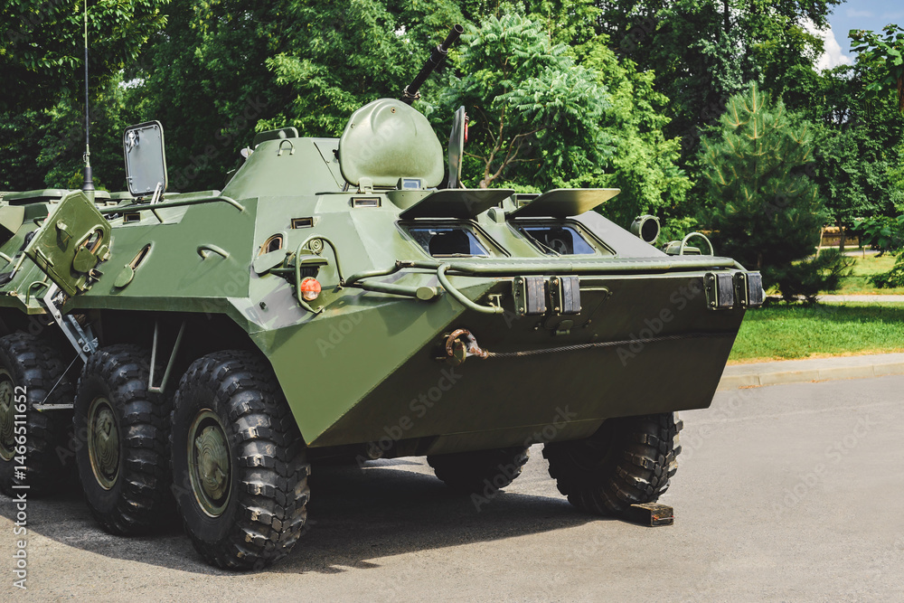 Fototapeta premium Military vehicle armored personnel carrier with camouflage coloring. Background of nature and trees.