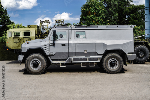 Swat team vehicle or special car grey color, standing in outdoors. Background of sky asphalt and trees.