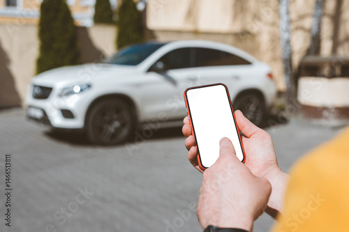 Mockup of a smartphone in a man's hands on the background of the car.
