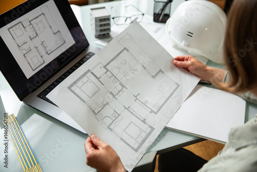 Architect holding and  working on a technichal blueprint project of new apartments in a multi-storey building .
