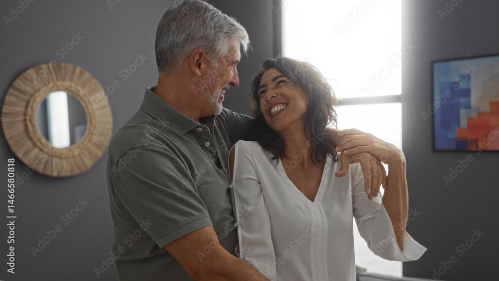 Fototapeta premium Couple smiling together in their stylish living room, capturing the essence of love and happiness in a modern home setting, with a woman wearing a white blouse and a man embracing her.