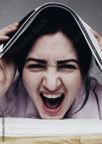 Alone working in office with a lot of documents. Yelling and screaming for bad results. Aggression, anger, frustration concept.