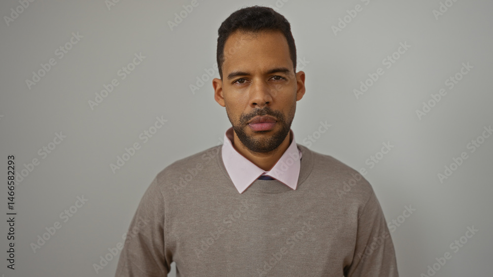 Young hispanic man with a neutral expression standing against an isolated white background showcasing fashion and style with focus on his attractive and confident presence. Young hispanic man with a neutral expression standing against an isolated white background showcasing fashion and style with focus on his attractive and confident presence.