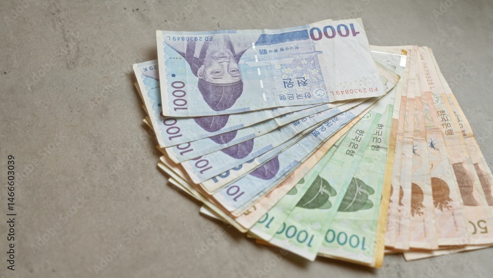 Fototapeta premium South korean banknotes spread out on a concrete surface highlighting various denominations of the won currency.