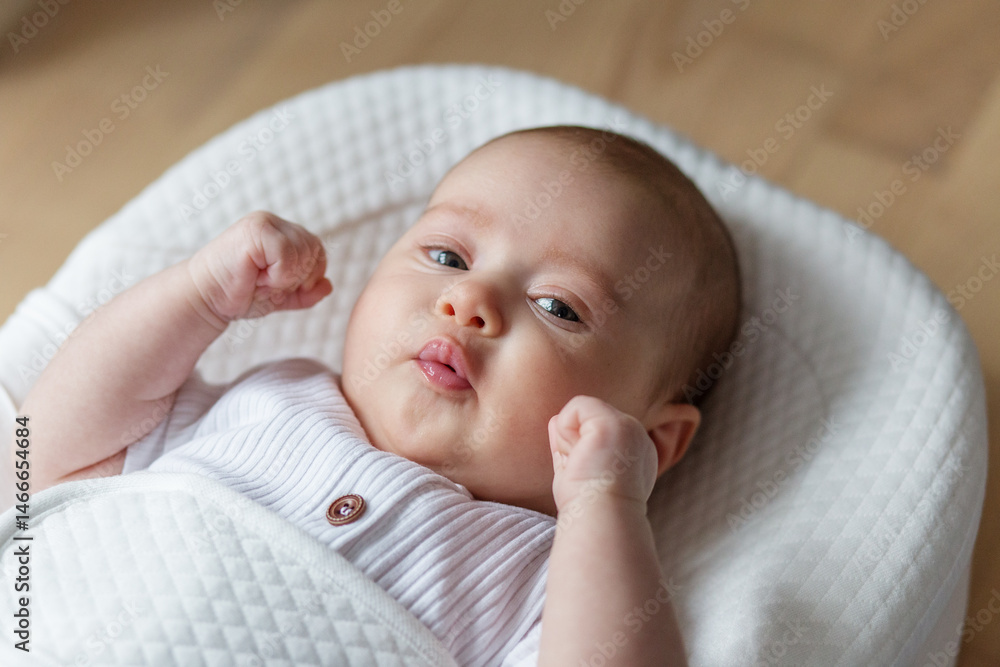 A two-month-old baby rests in a soft white ergonomic cocoon. Close up A two-month-old baby rests in a soft white ergonomic cocoon. Close up