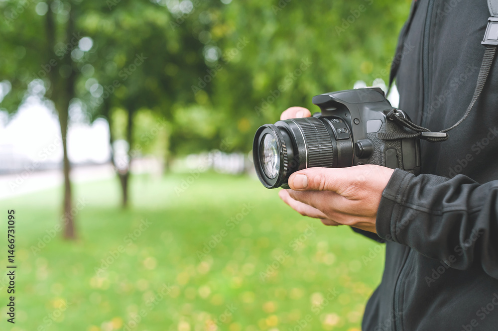 Fototapeta premium Camera in the hands of a man in a beautiful park.