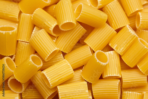 Dry mezzi rigatoni pasta tubes in a detailed close-up view showing ridges, cylindrical shape, and raw texture, ideal for Italian food concepts