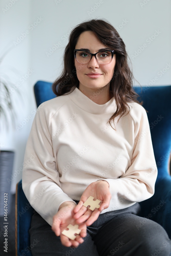 Obraz premium Young caucasian female holding puzzle pieces indoors on blue chair