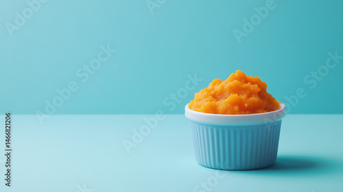 Creamy orange puree in a white bowl on a bright blue background