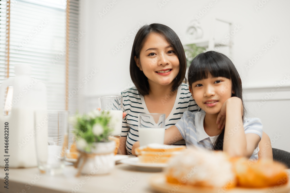Happy Asian family enjoying breakfast with milk at the kitchen table at home.Parents and daughter enjoying breakfast with milk in a warm, inviting kitchen. Happy Asian family enjoying breakfast with milk at the kitchen table at home.Parents and daughter enjoying breakfast with milk in a warm, inviting kitchen.