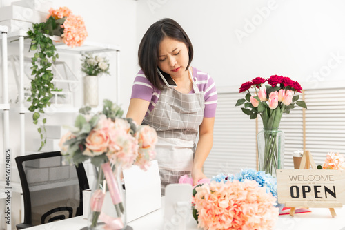 A couple of Asian entrepreneurs using their smartphones to sell flowers online.