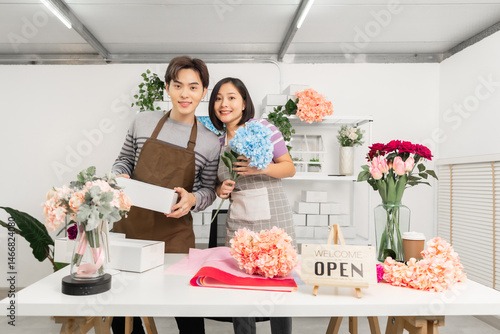 A couple of Asian entrepreneurs using their smartphones to sell flowers online.