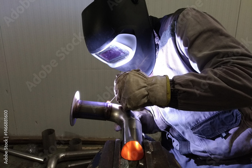 Photos welder welds stainless steel pipe with tungsten electrode in protective gas envi