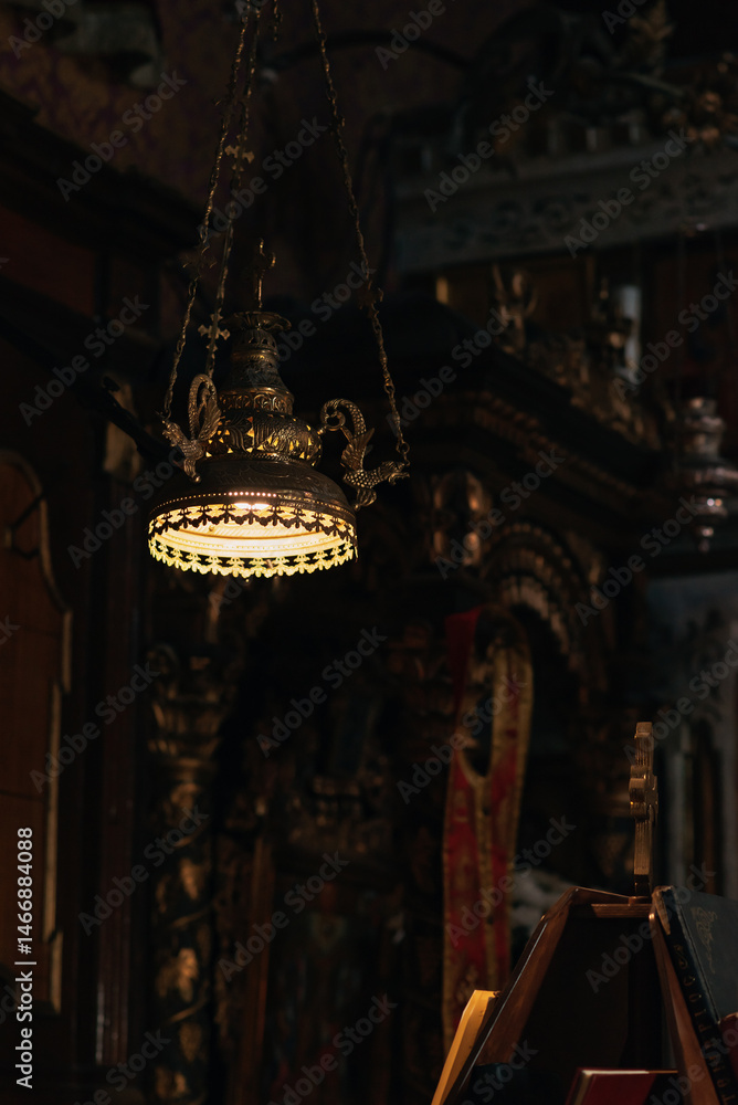Antique illuminated lamp hanging in an old memorial chapel.