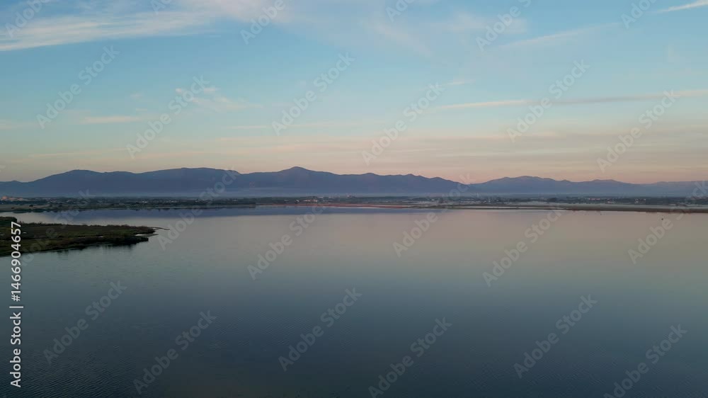 Aerial: Sideway drone flight during sunrise along coastline with mountain backdrop Aerial: Sideway drone flight during sunrise along coastline with mountain backdrop