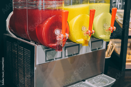 Close-up of three slushy machines with red and yellow flavors.