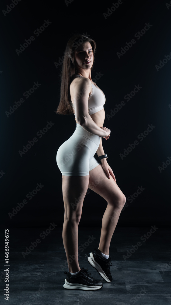Fototapeta premium Young beautiful woman with athletic body on dark background. Fitness girl
