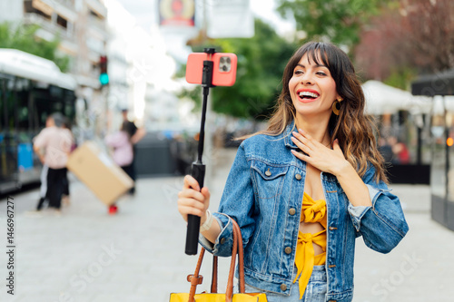 Influencer creating video content with selfie stick and smartphone in urban environment