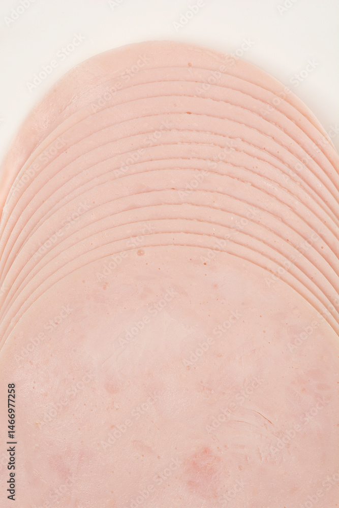 A close-up shot of a stack of thinly sliced chicken breast deli meat