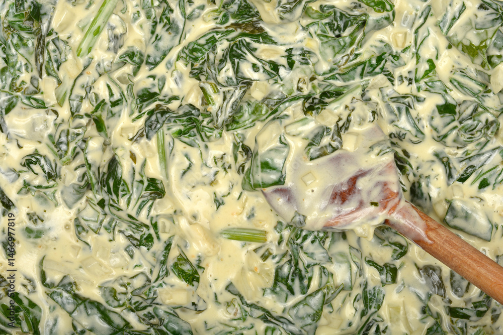 A close-up overhead shot shows creamy green spinach being stirred with a wooden spoon