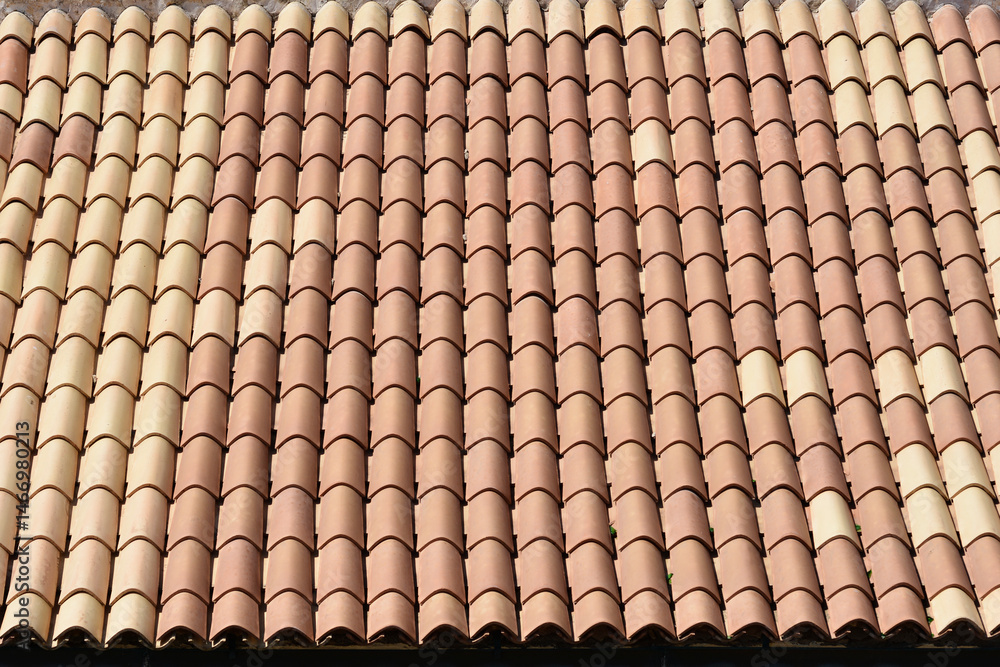 A close-up of a roof covered with rows of red and beige barrel tiles
