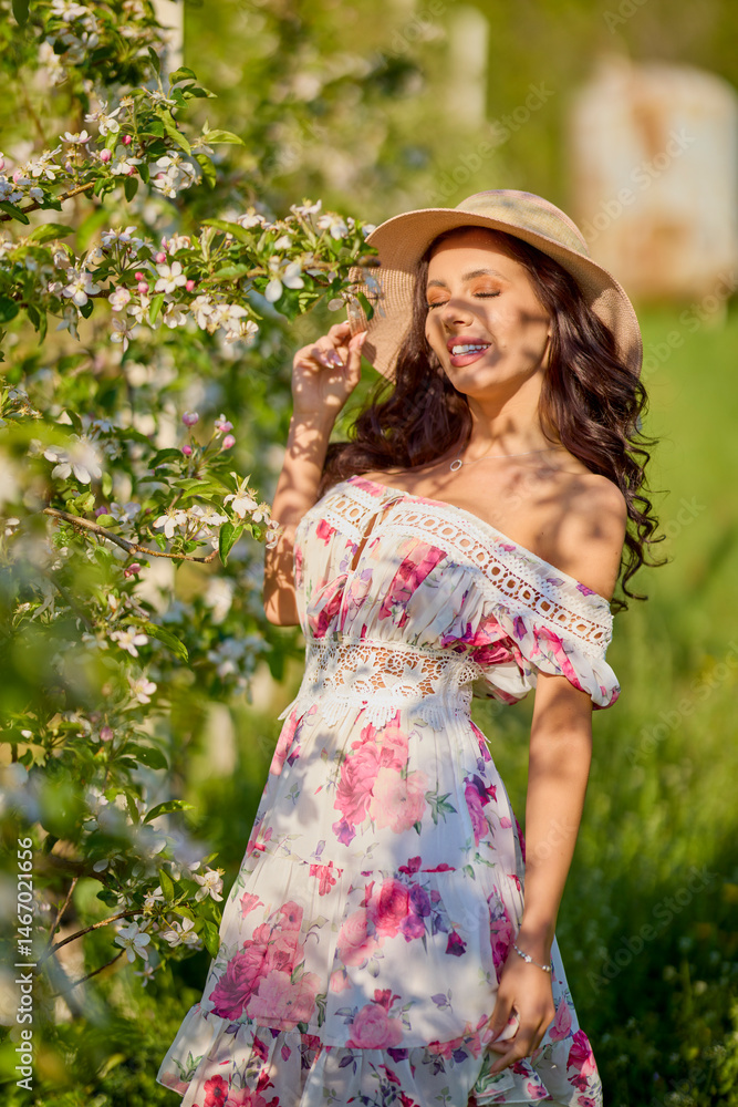 portrait of a beautiful woman in a dress in a blooming apple orchard enjoying a sunny spring day