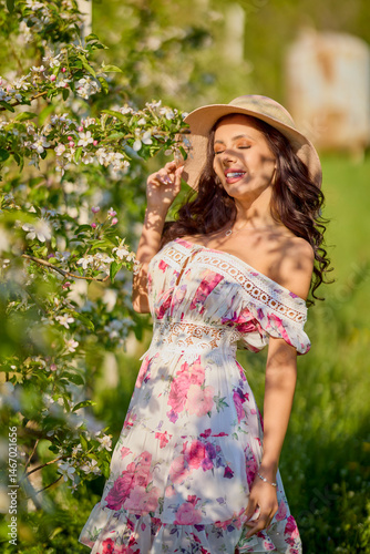 Obraz na płótnie portrait of a beautiful woman in a dress in a blooming apple orchard enjoying a sunny spring day w salonie