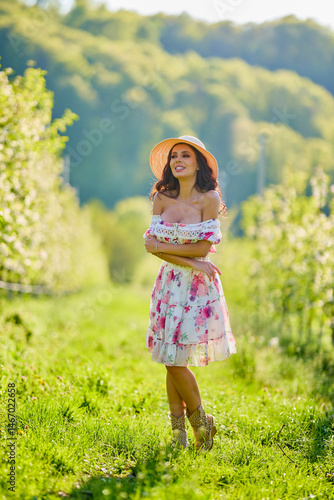 Obraz na płótnie Full body portrait of a beautiful woman in a dress in a blooming apple orchard on a sunny spring day w salonie