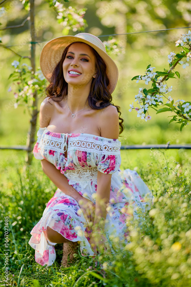 portrait of a beautiful woman in a dress in a blooming apple orchard enjoying a sunny spring day