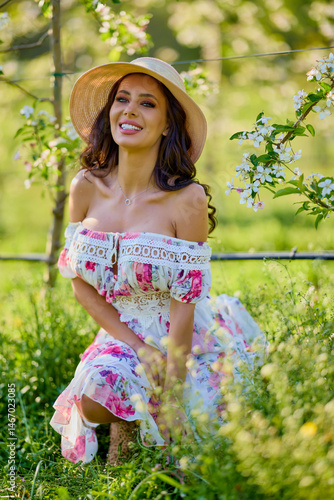 Obraz na płótnie portrait of a beautiful woman in a dress in a blooming apple orchard enjoying a sunny spring day w salonie