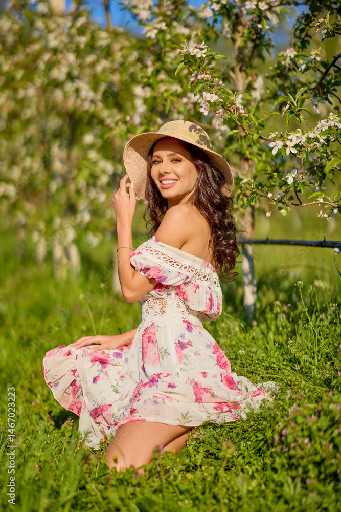portrait of a beautiful woman in a dress in a blooming apple orchard enjoying a sunny spring day