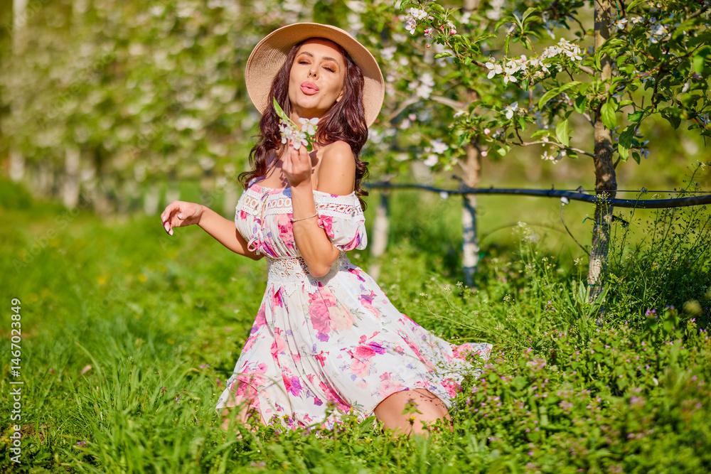 portrait of a beautiful woman in a dress in a blooming apple orchard enjoying a sunny spring day