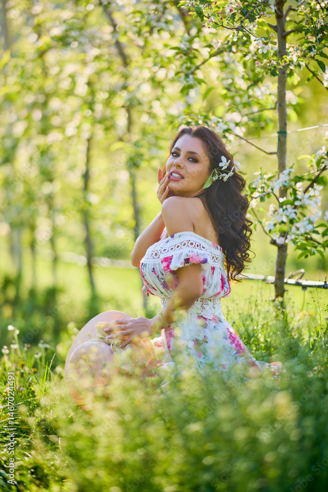 portrait of a beautiful woman in a dress in a blooming apple orchard enjoying a sunny spring day