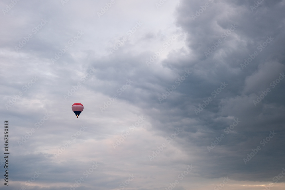 Fototapeta premium Hot air balloon flying under dramatic cloudy sky